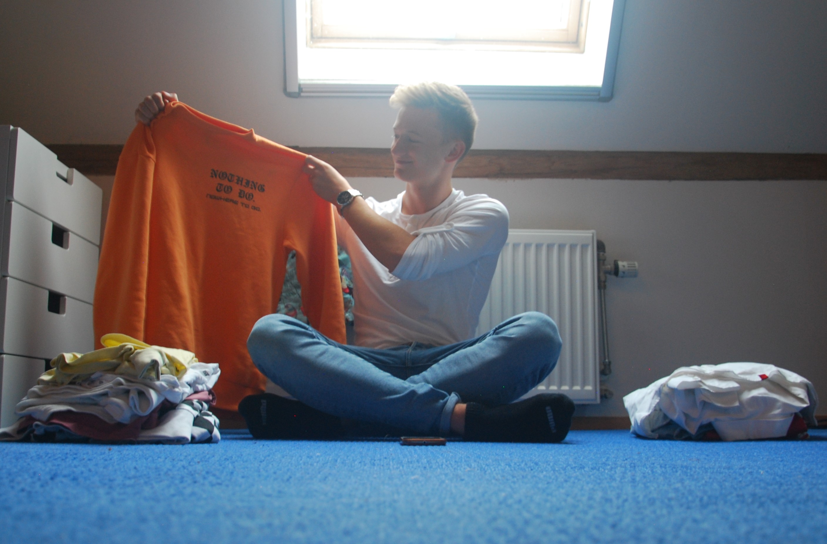 Jongen kijkt naar kleren en lacht