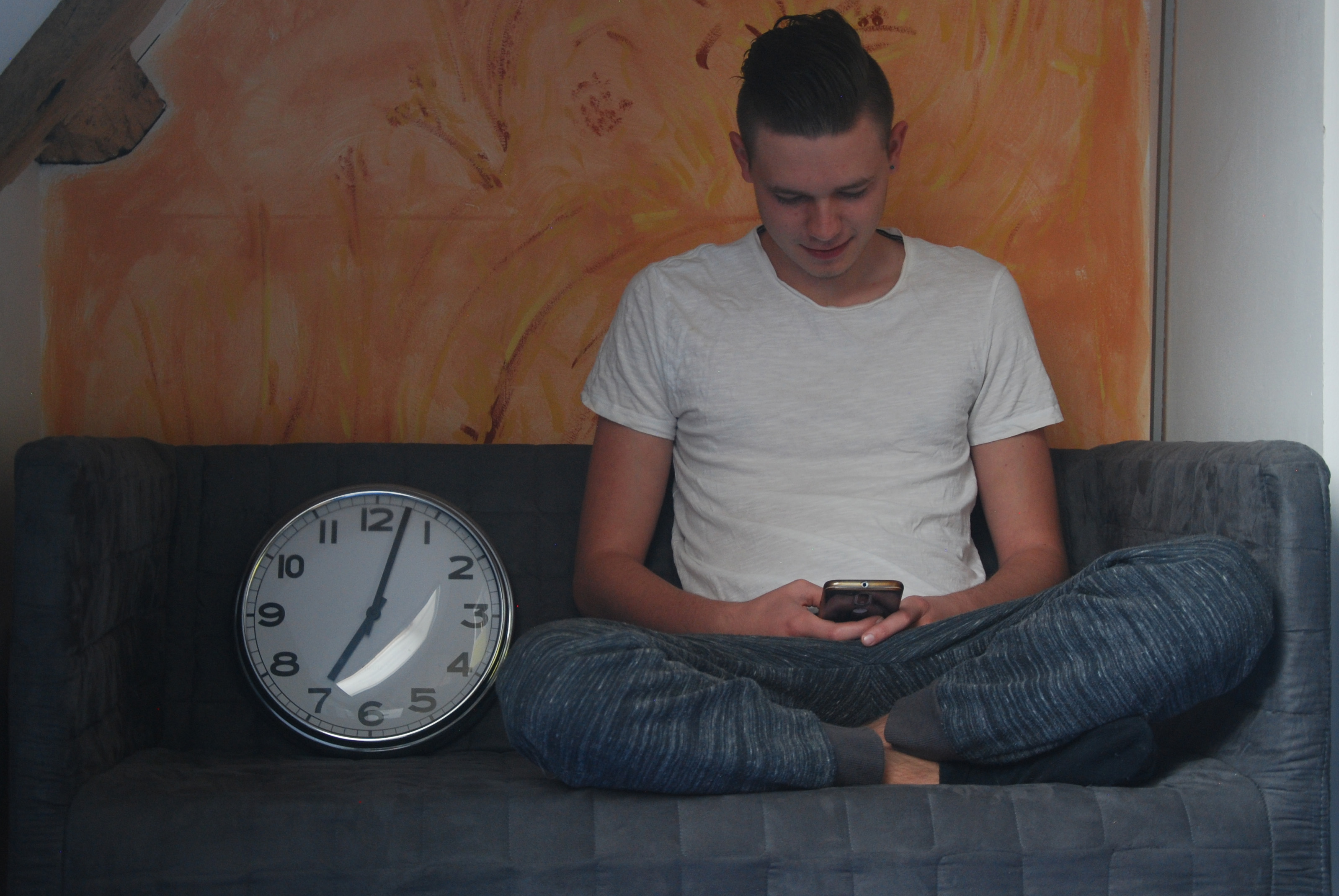 Jongen kijkt op smartphone en glimlacht een beetje